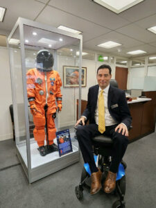 Chris Carrino in front of encased space suit display.